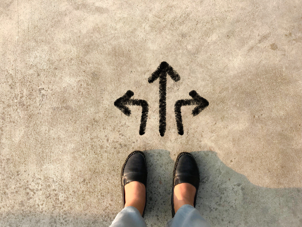 woman's feet standing over three arrows pointing in different directions